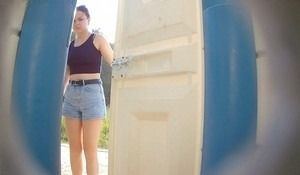 Молодая девушка согнувшись писает в биотуалете